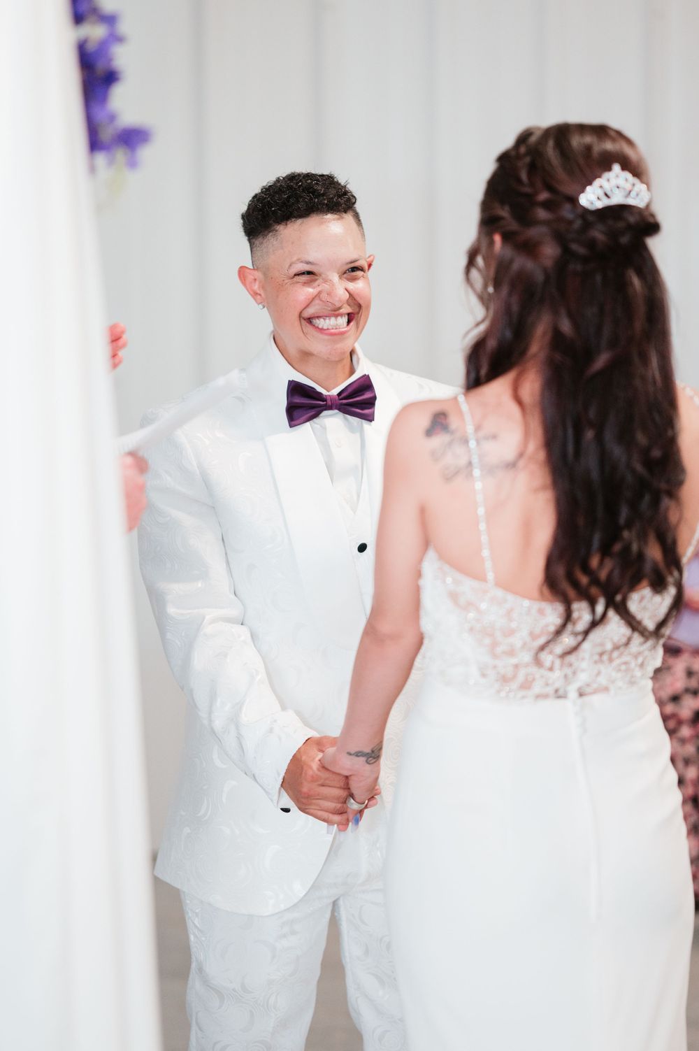 Couple in white wedding attire sharing joyful moment together.