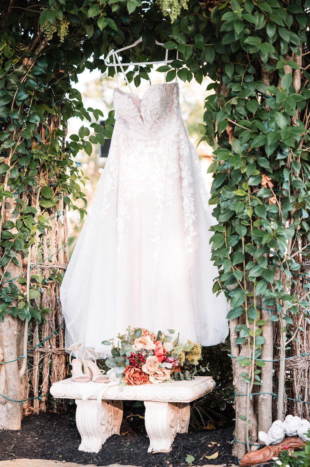 White wedding dresses hanging among green vines creating a romantic garden display.