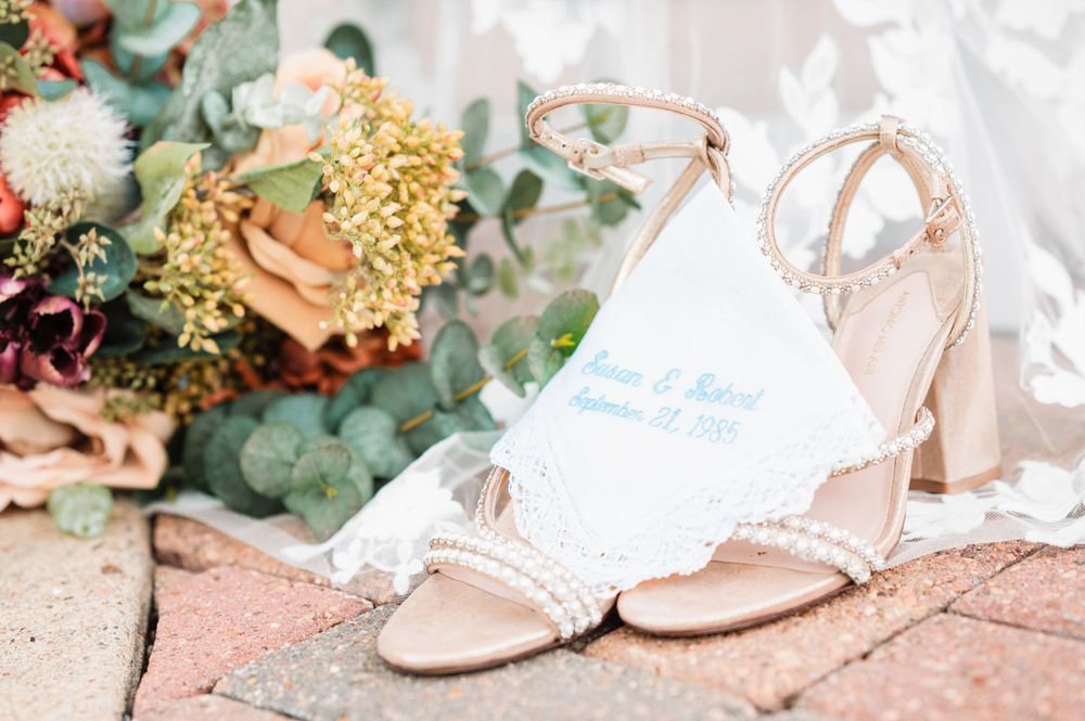 Delicate bridal accessories including shoes and floral details arranged on a light background.