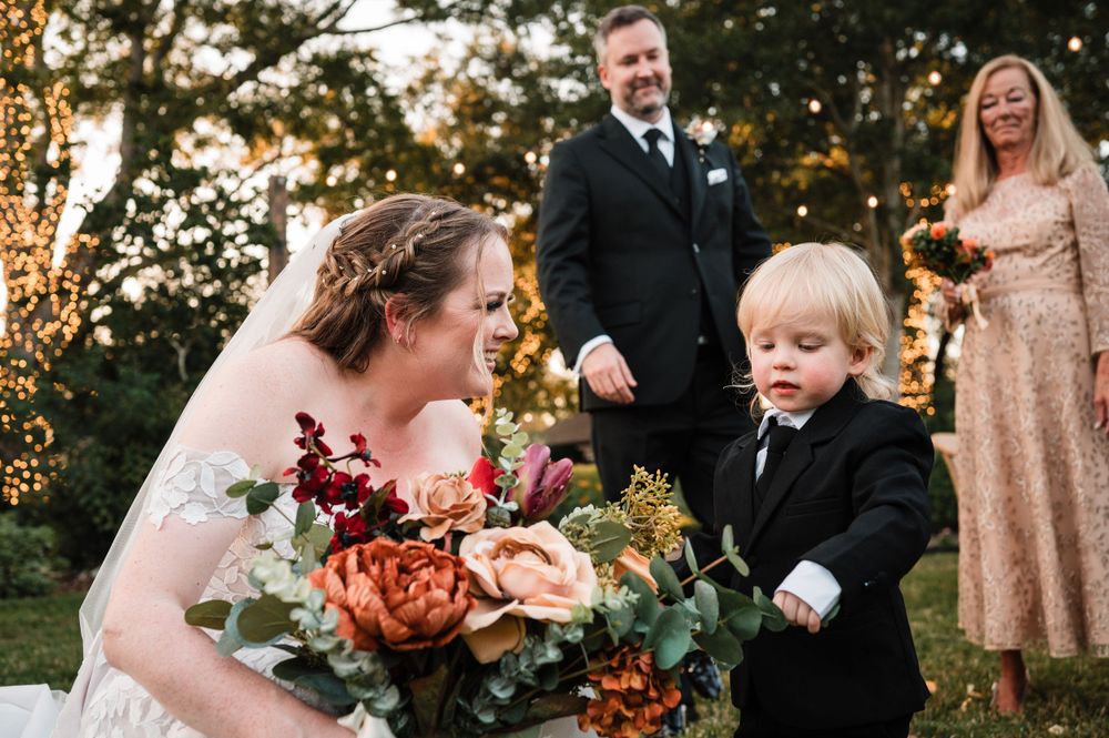 Wedding party celebrating outdoors during golden hour with autumn-colored floral bouquets.