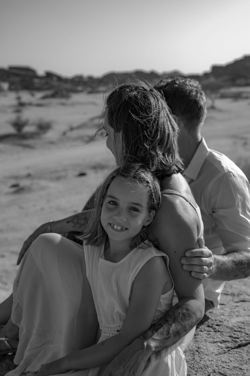 Intimate family moment captured in black and white against desert scenery.