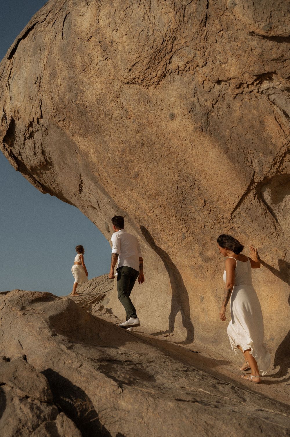 People walking along natural rock formation in desert setting.