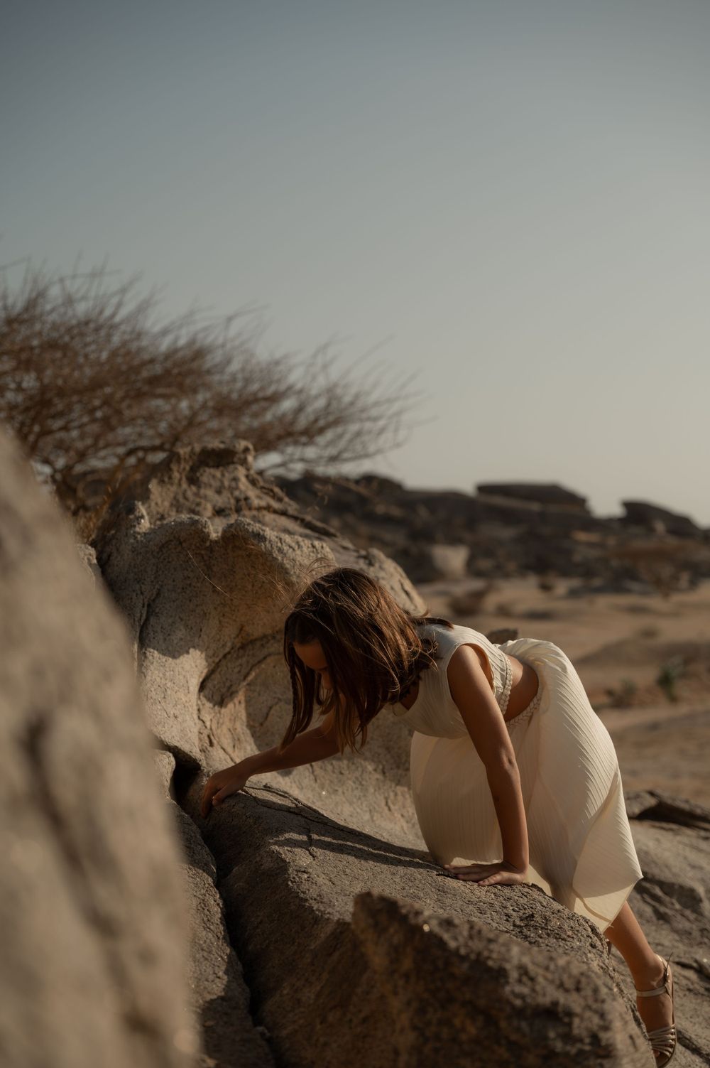 Artistic desert photoshoot with dramatic rock formations at dusk.