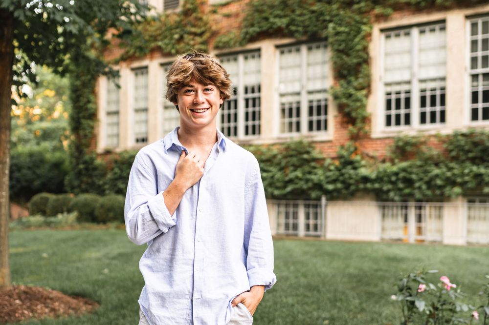 Portrait of a senior boy posing in front of an ivy covered building at Aquinas College in Grand Rapids.
