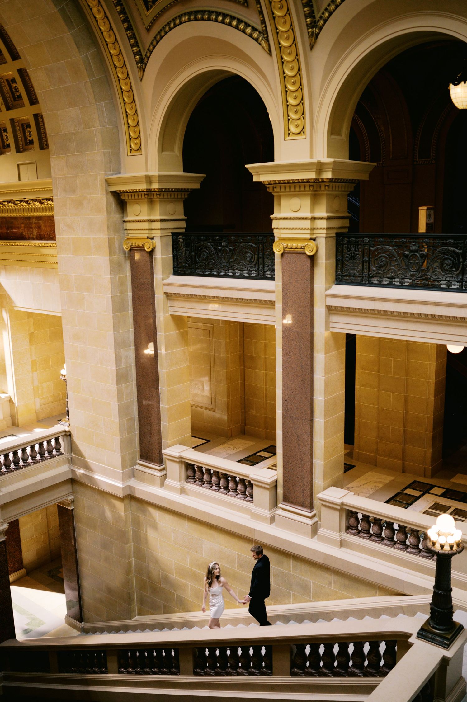 Elegant marble staircase with ornate columns and arches inside a grand historic government building or museum interior.
