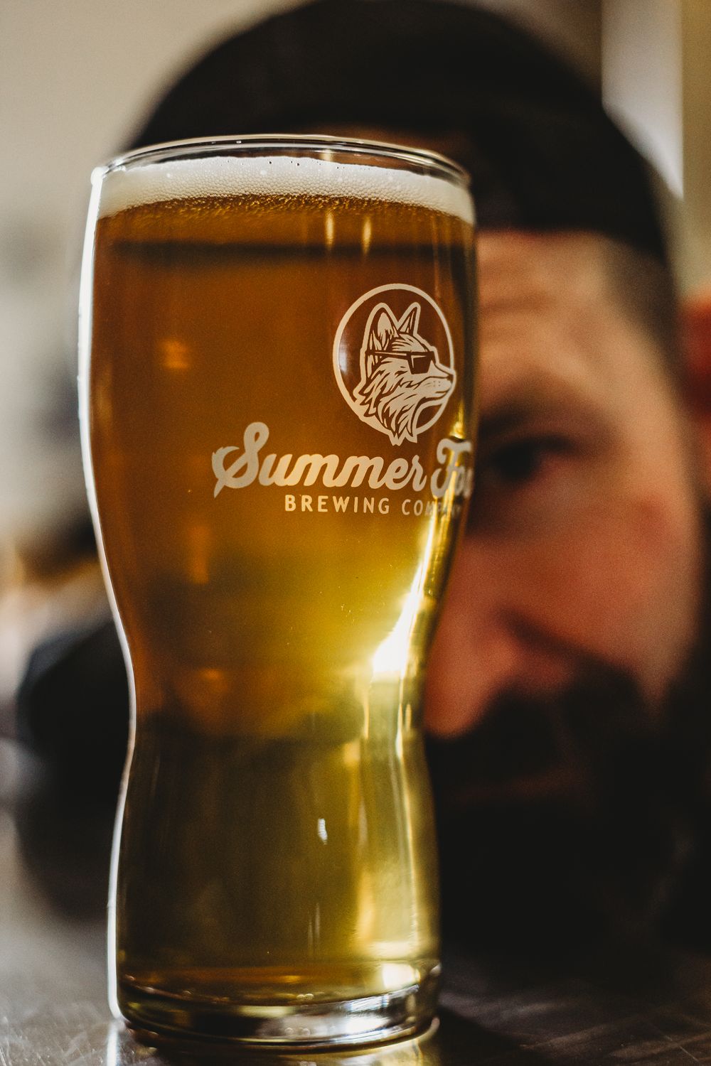 Summer Fox beer with owner peering through the glass