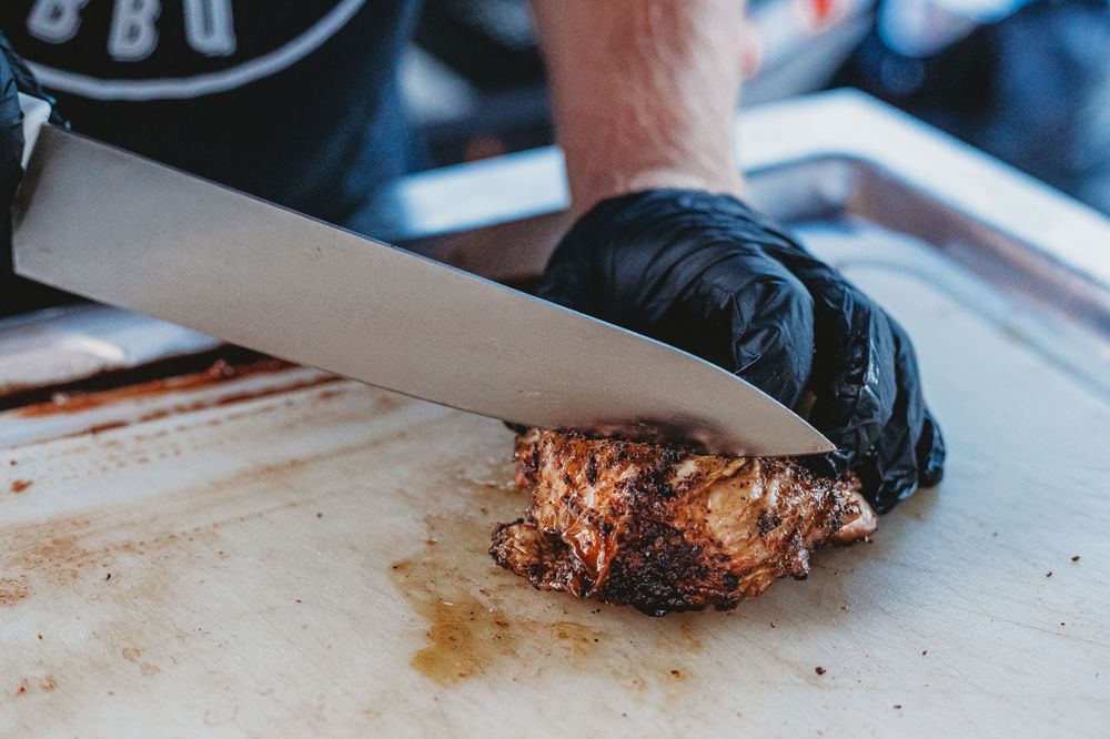Close-up of hands slicing smoked brisket with a chef's knife