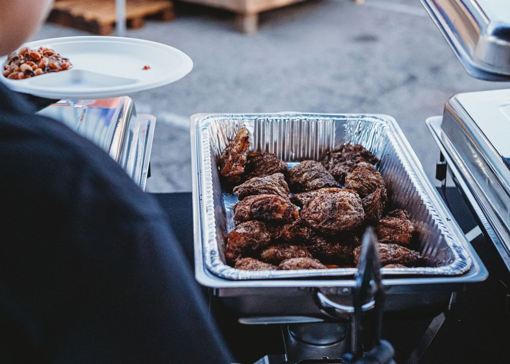 Foil tray of smoked BBQ meat on an outdoor prep table