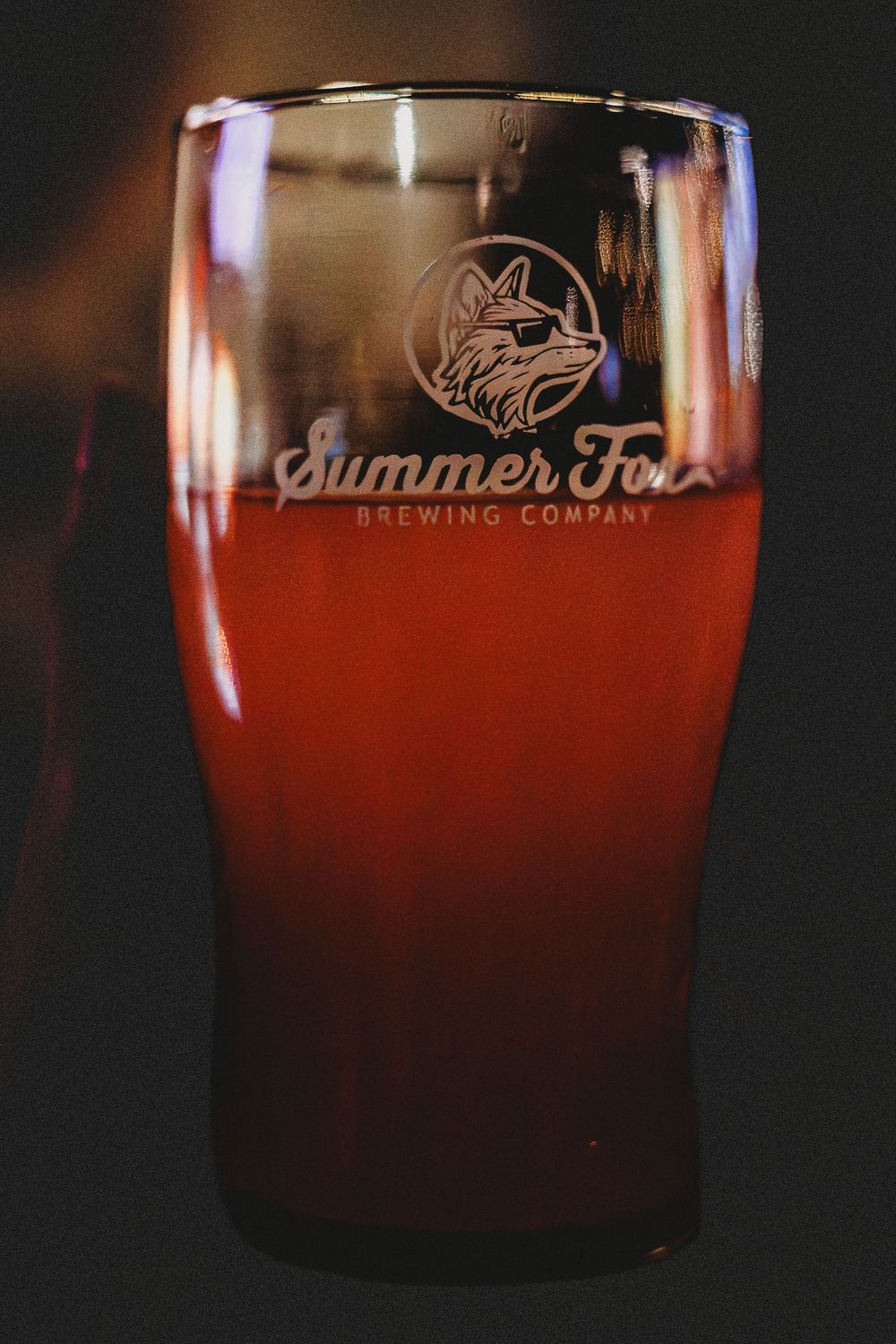 Summer Fox beer glass with a red beer and dark background