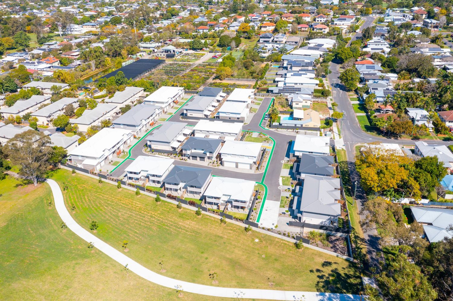 Aerial view of a modern residential development beside a green park in a suburban Queensland neighborhood.