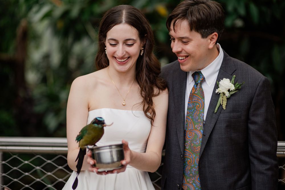 A happy couple shares a joyful moment during their outdoor wedding ceremony with natural greenery in the background.