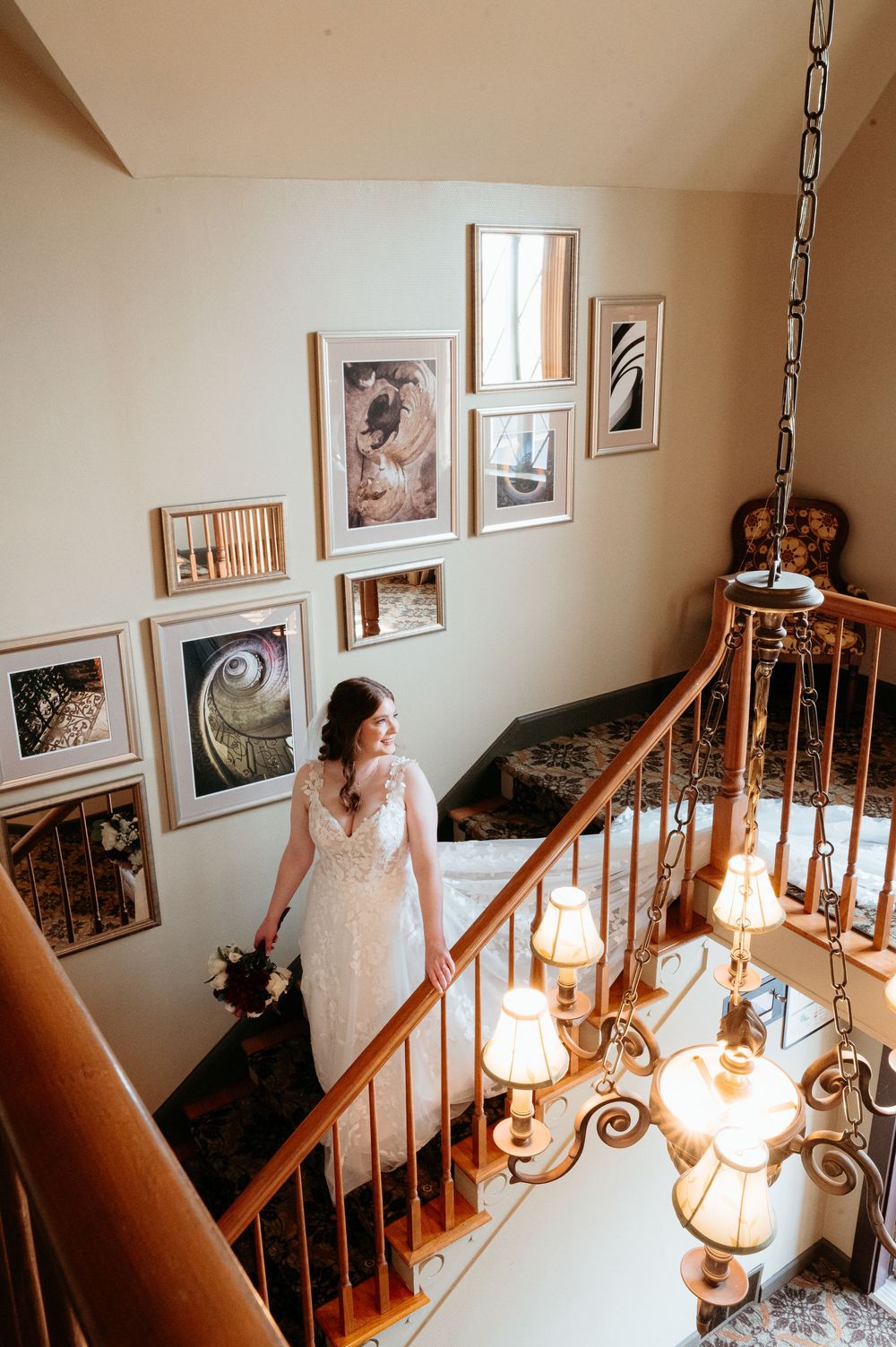 Wedding dress detail shots on wooden staircase with vintage light fixtures and framed photos. Bridal Portraits. Wedding day in Michigan.
