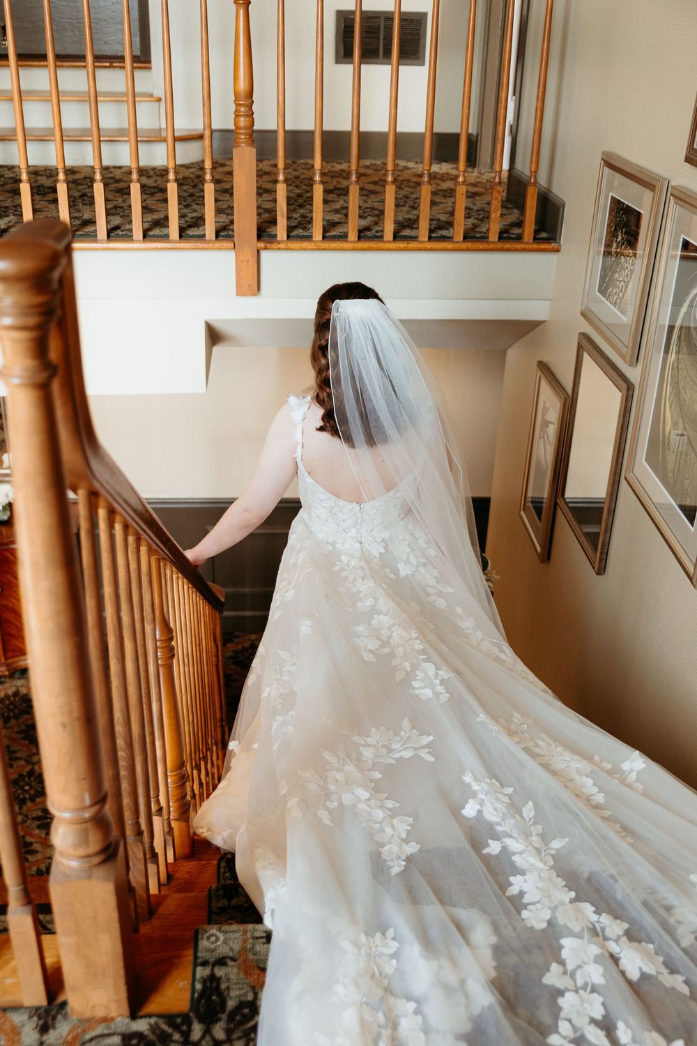 Elegant white wedding dress with lace details displayed on wooden staircase. Bridal portraits on the wedding day in Detroit Michigan.