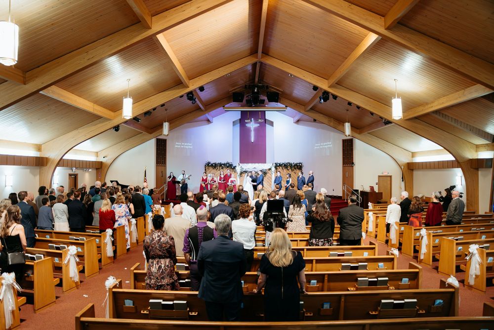 Interior view of a church sanctuary with wooden beams and pews during a wedding ceremony.