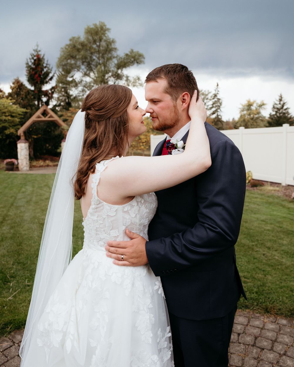 A romantic outdoor wedding moment with the bride and groom embracing against a cloudy stormy sky. Fall Wedding in Michigan.