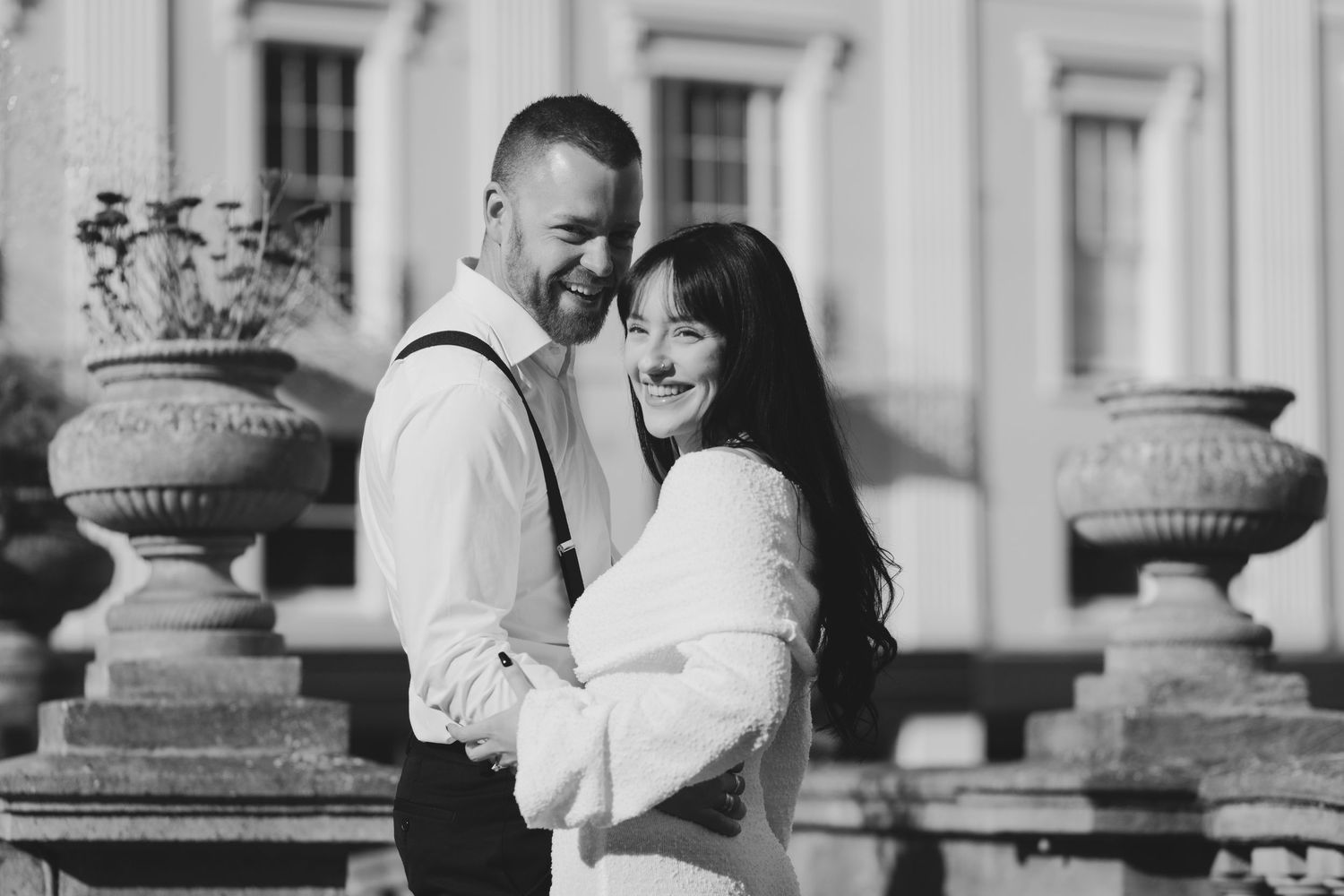 In the heart of the Cotswolds a romantic couple embraces and shares moments among elegant stone columns in a classic architectural setting.