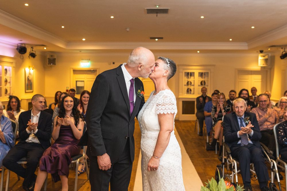Wedding guests watch as a couple shares their first dance in an elegant reception hall with recessed lighting.