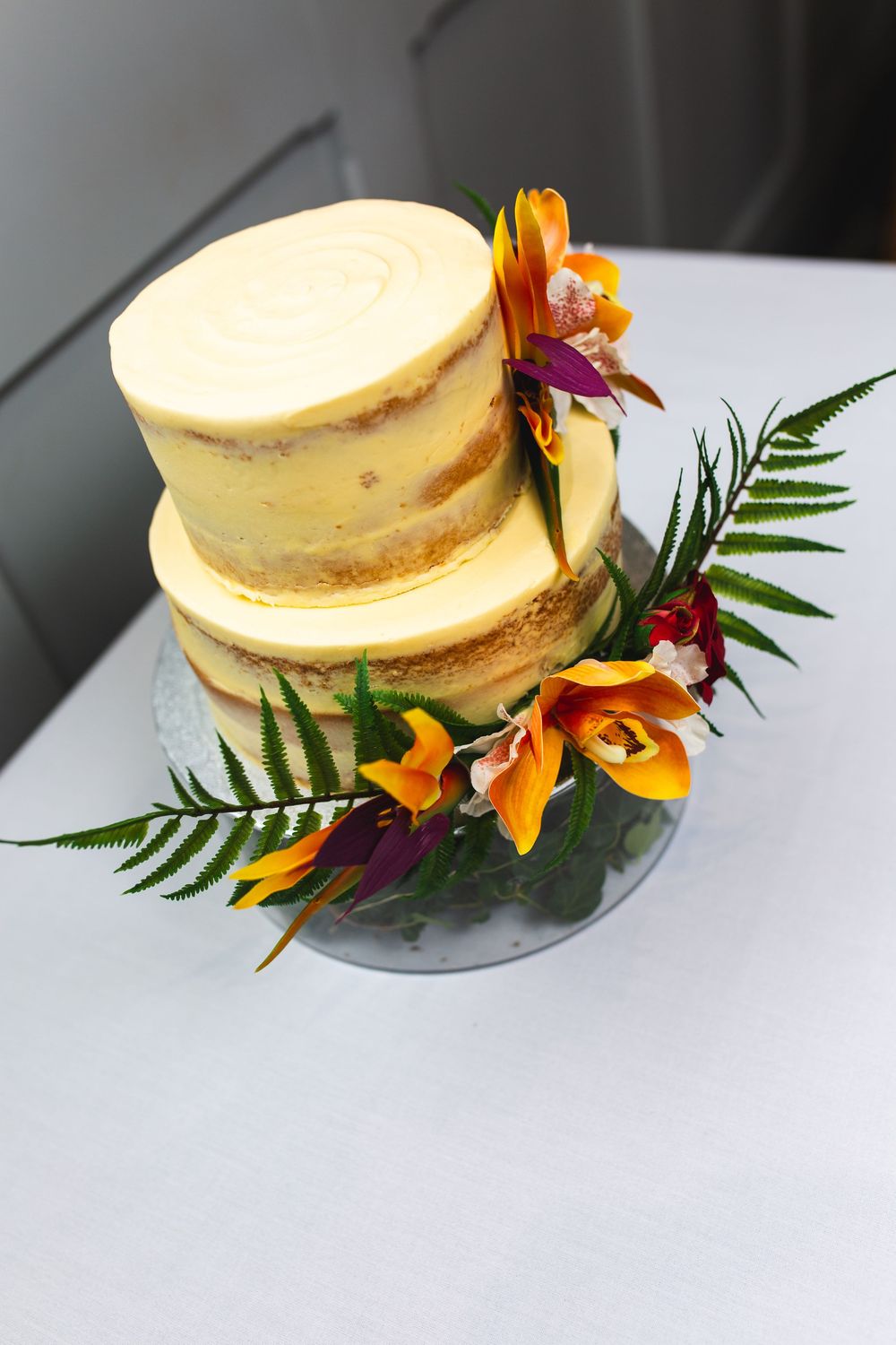 Elegant cheesecake dessert garnished with orange flowers and fern leaves on white plate.