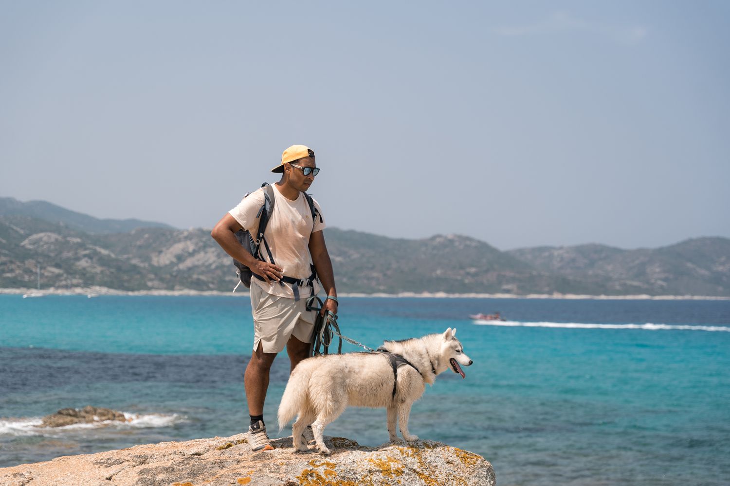 un chien et son maitre sur un rocher avec la plage de saleccia en arrière-plan
