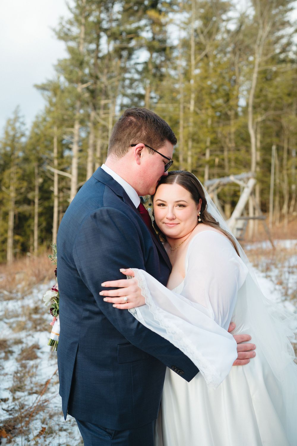 A romantic winter wedding photoshoot sequence showing a couple embracing in a snowy forest setting.