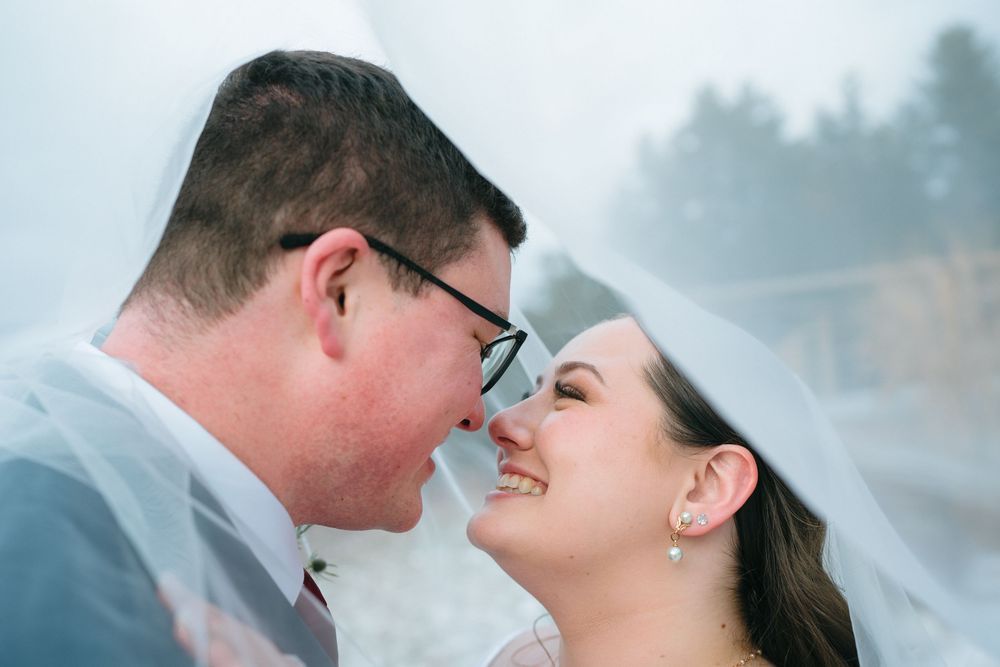 A happy couple shares an intimate moment together in the fog, their faces close as they smile at each other.