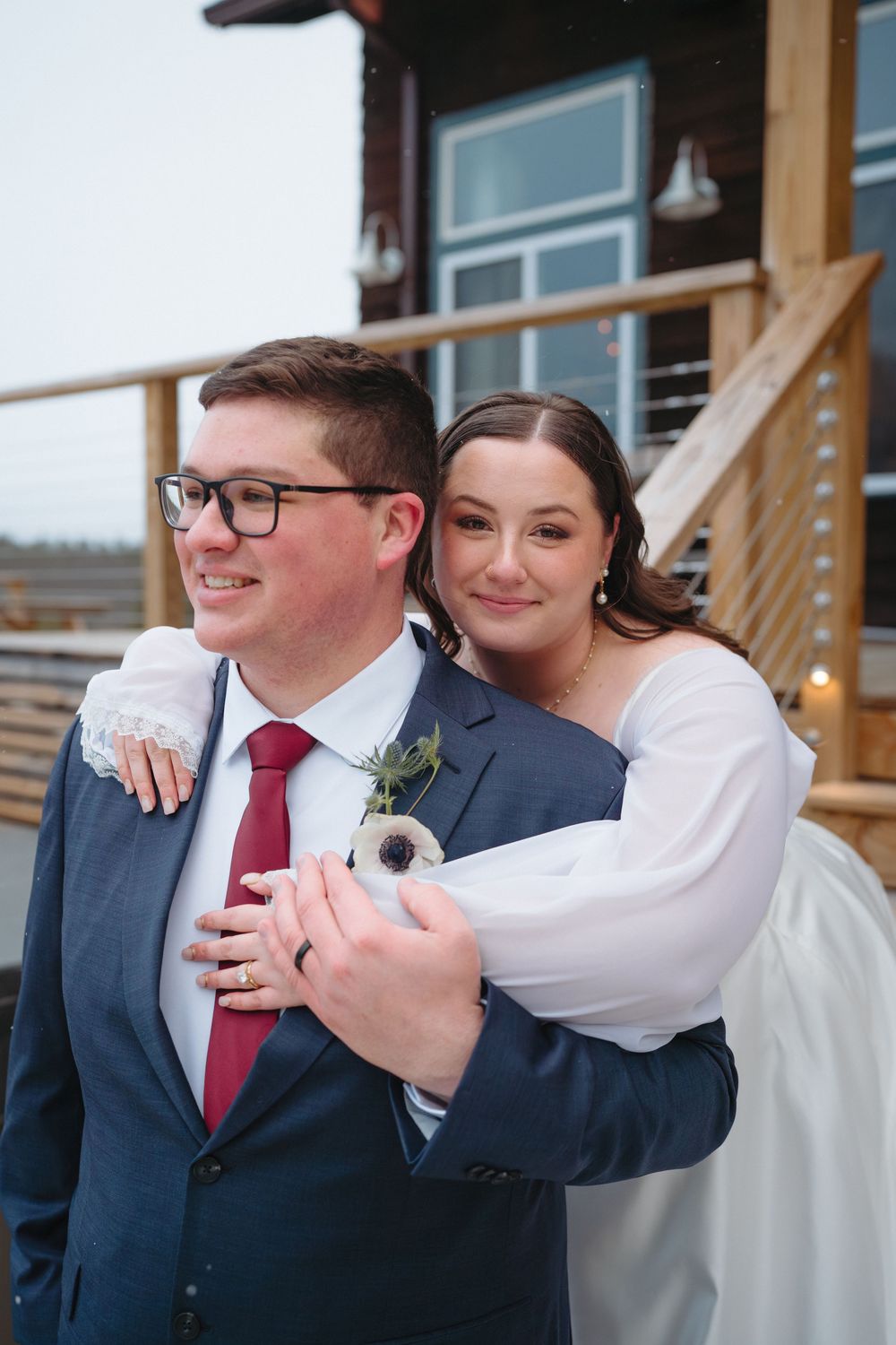 A couple shares an intimate moment during their winter wedding celebration on a rustic wooden porch.