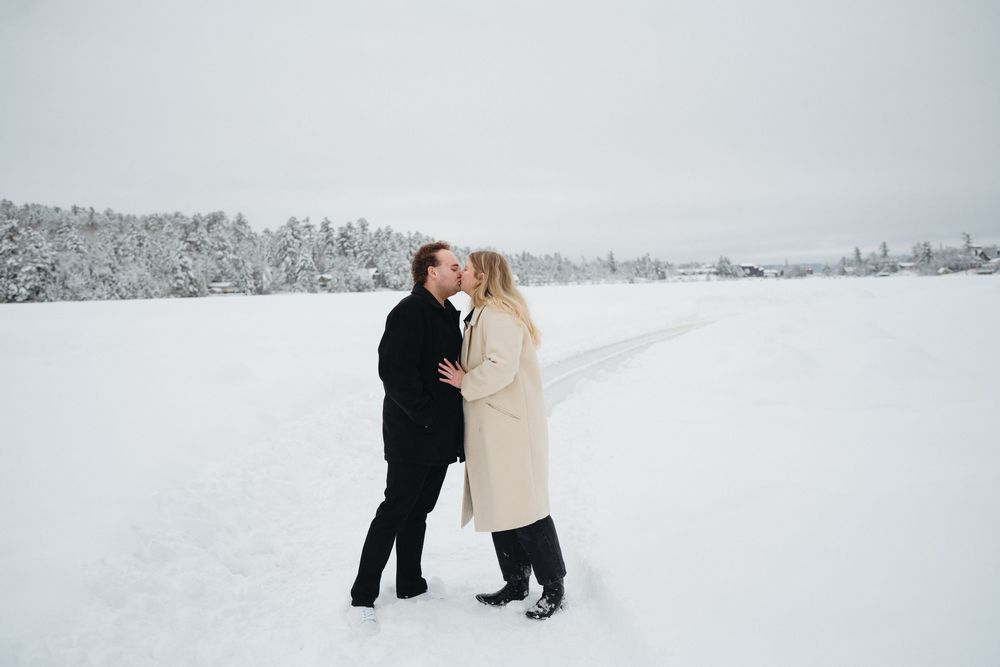 Two people walk together through a snowy winter landscape on a cold foggy day.