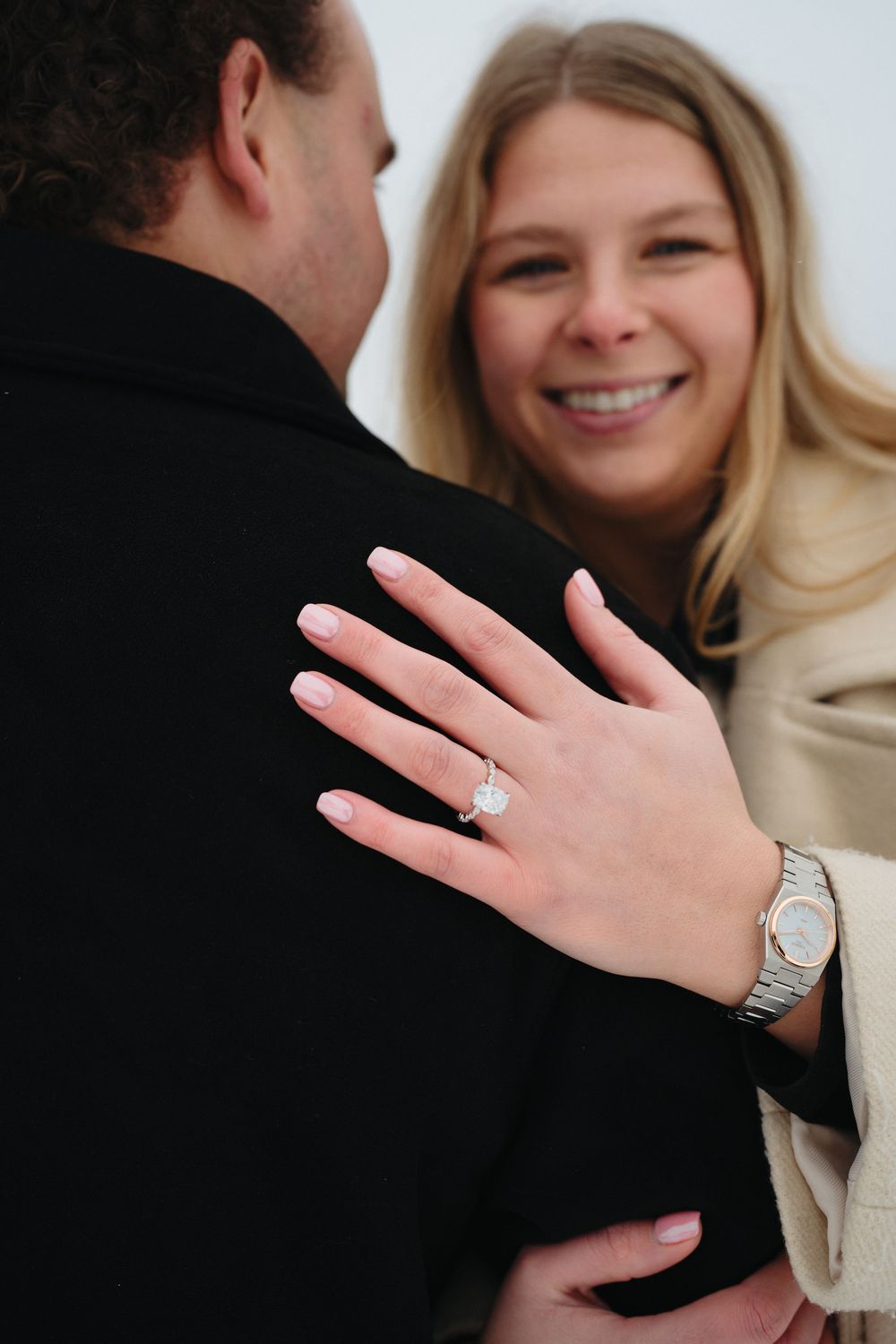 A couple embraces while showing off a sparkling engagement ring in a series of candid photos.