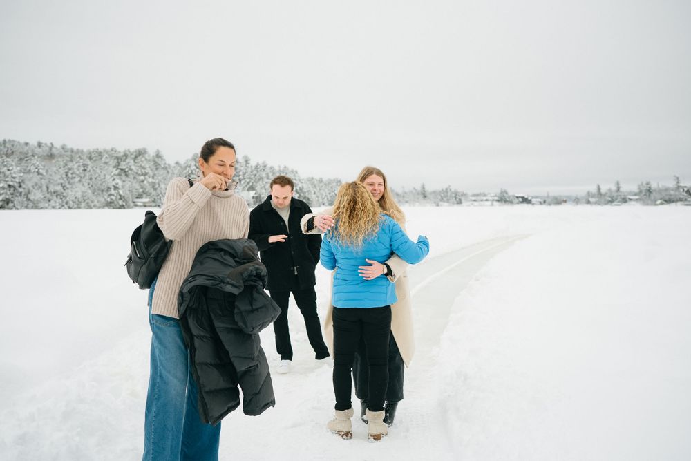 A group of people play and throw snowballs at each other in a snowy winter landscape.