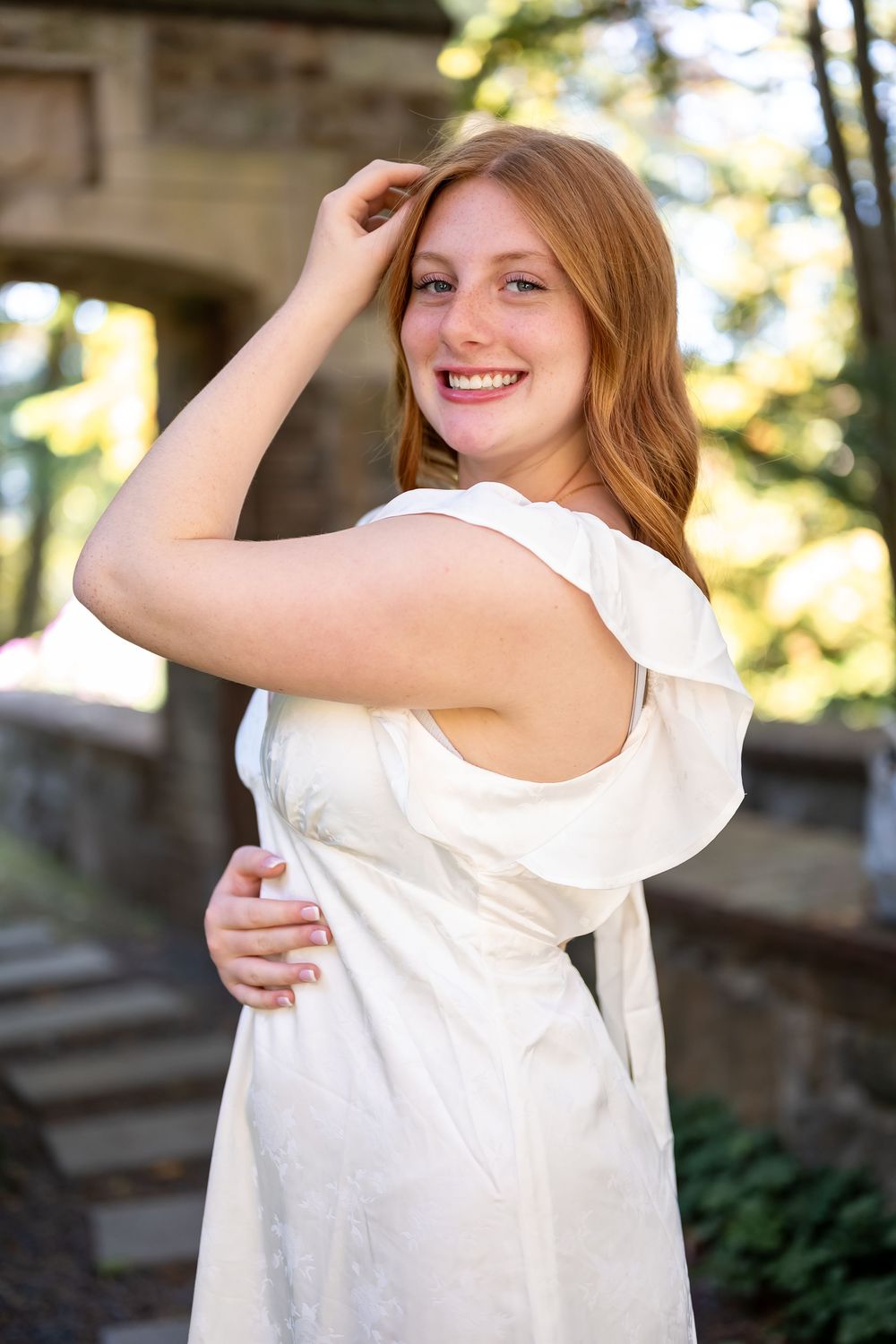 A person in a sleeveless white top poses outdoors while smiling and touching their hair in a series of photos.
