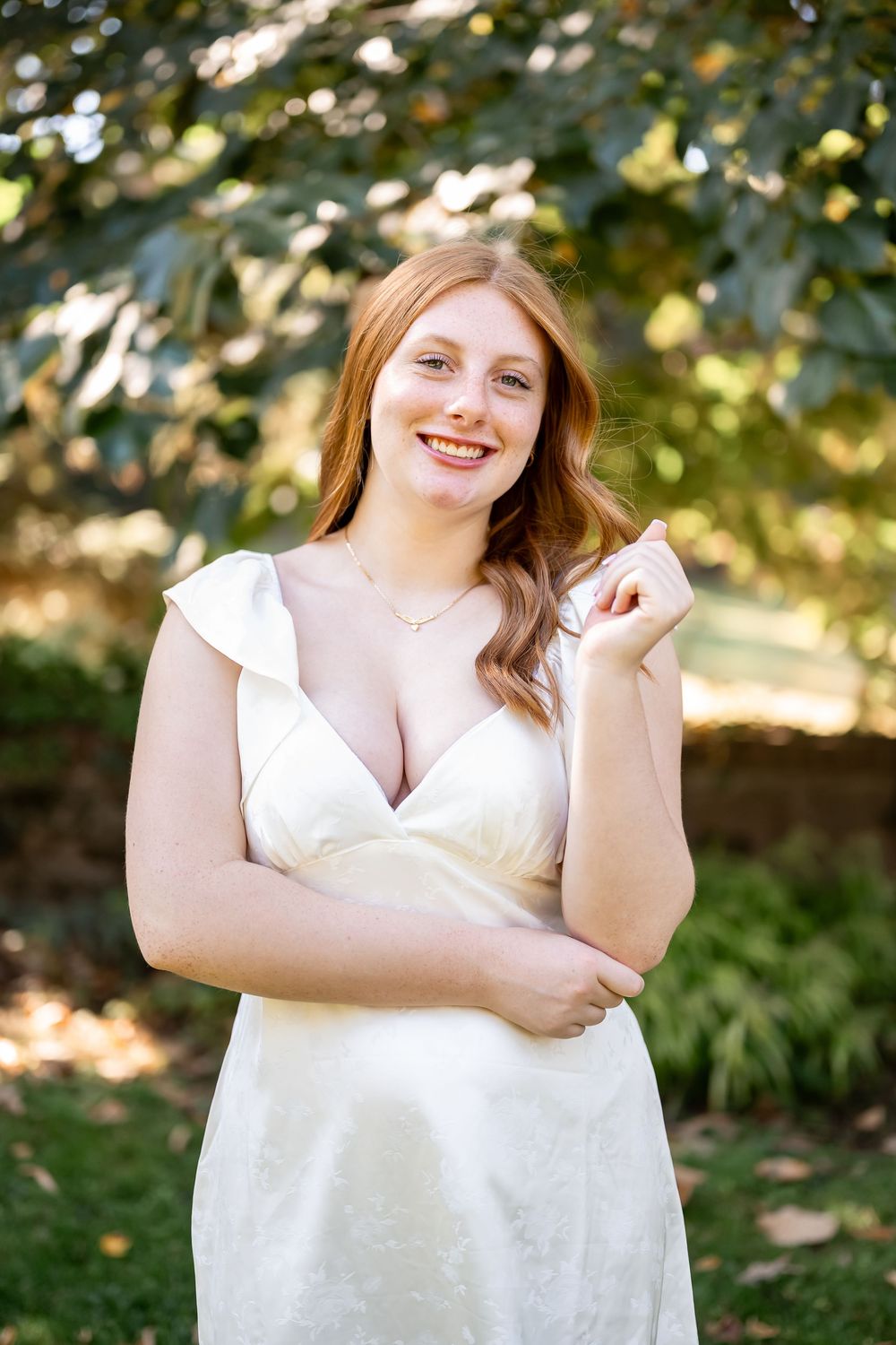 Portrait photos taken outdoors with natural lighting and autumn foliage in the background wearing a white sleeveless top.