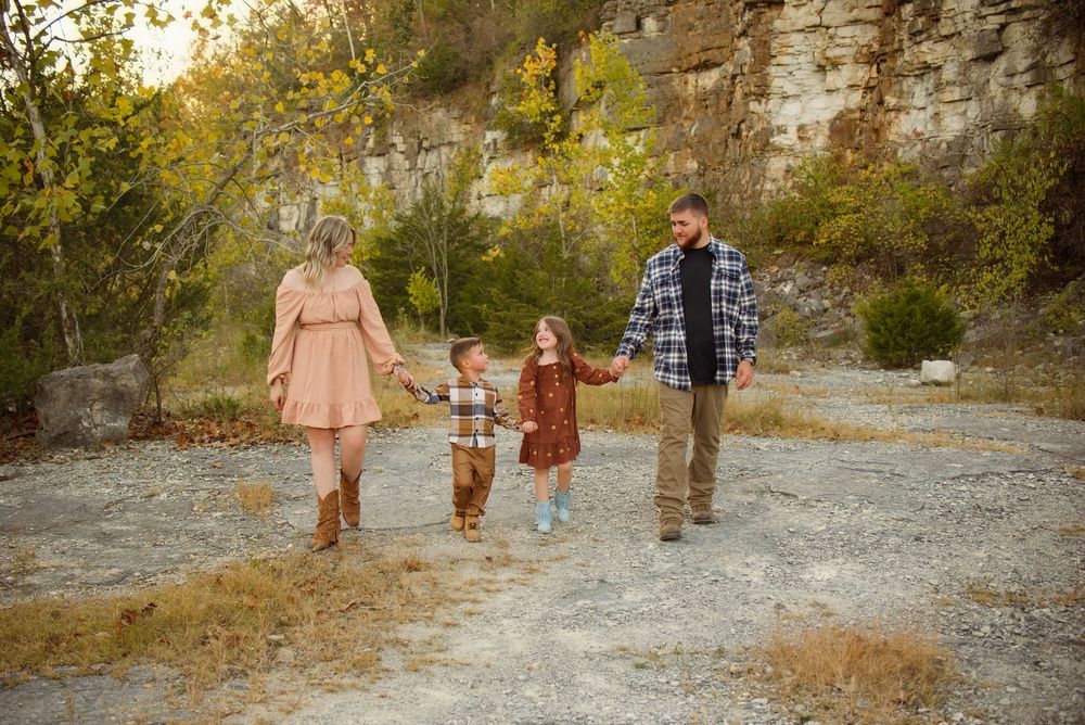 Family walking together on a rocky path surrounded by fall foliage and cliffs.