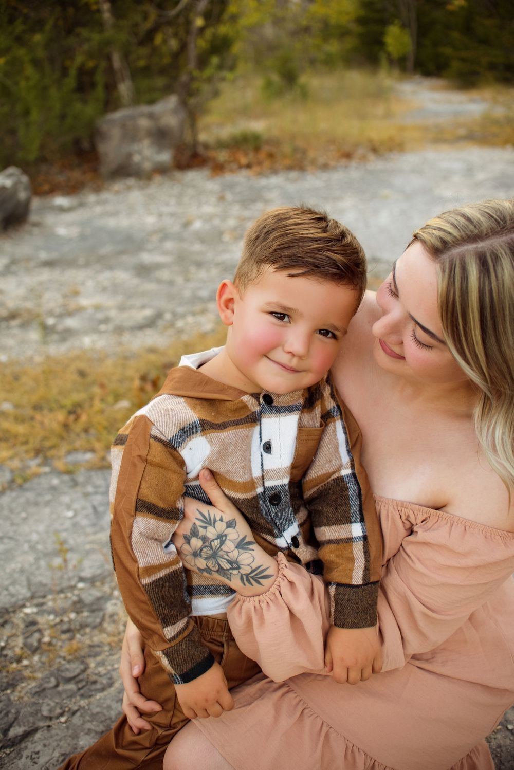 A tender moment between parent and child in autumn clothing against a rocky outdoor backdrop.