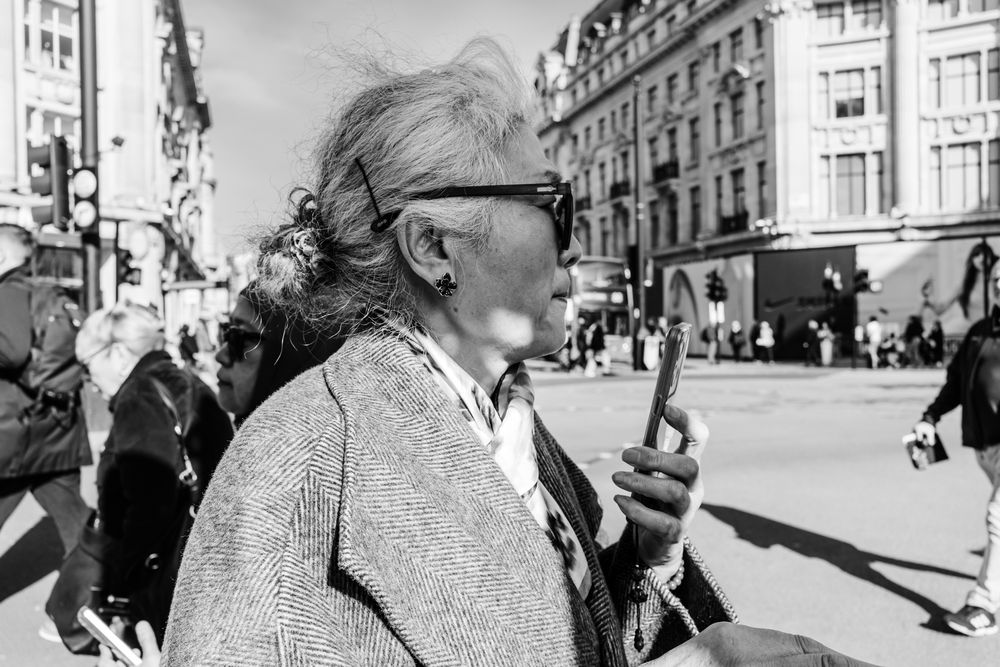 Black and white street photography captures candid moments of people walking through a city in vintage urban setting.