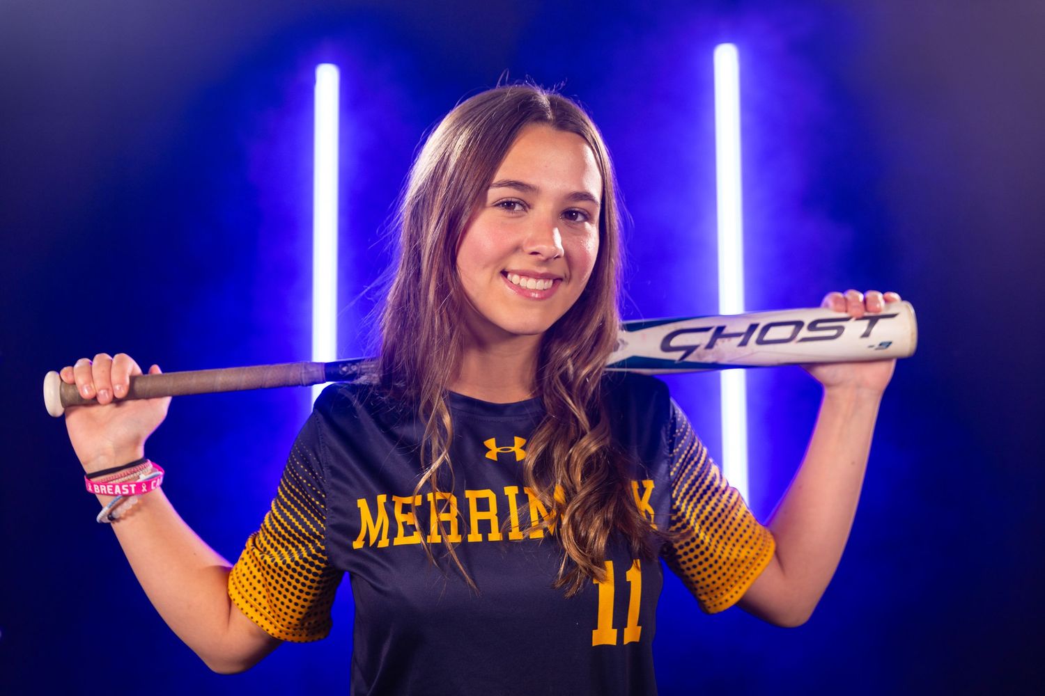 Softball player poses with bat under dramatic blue lighting for team photos.