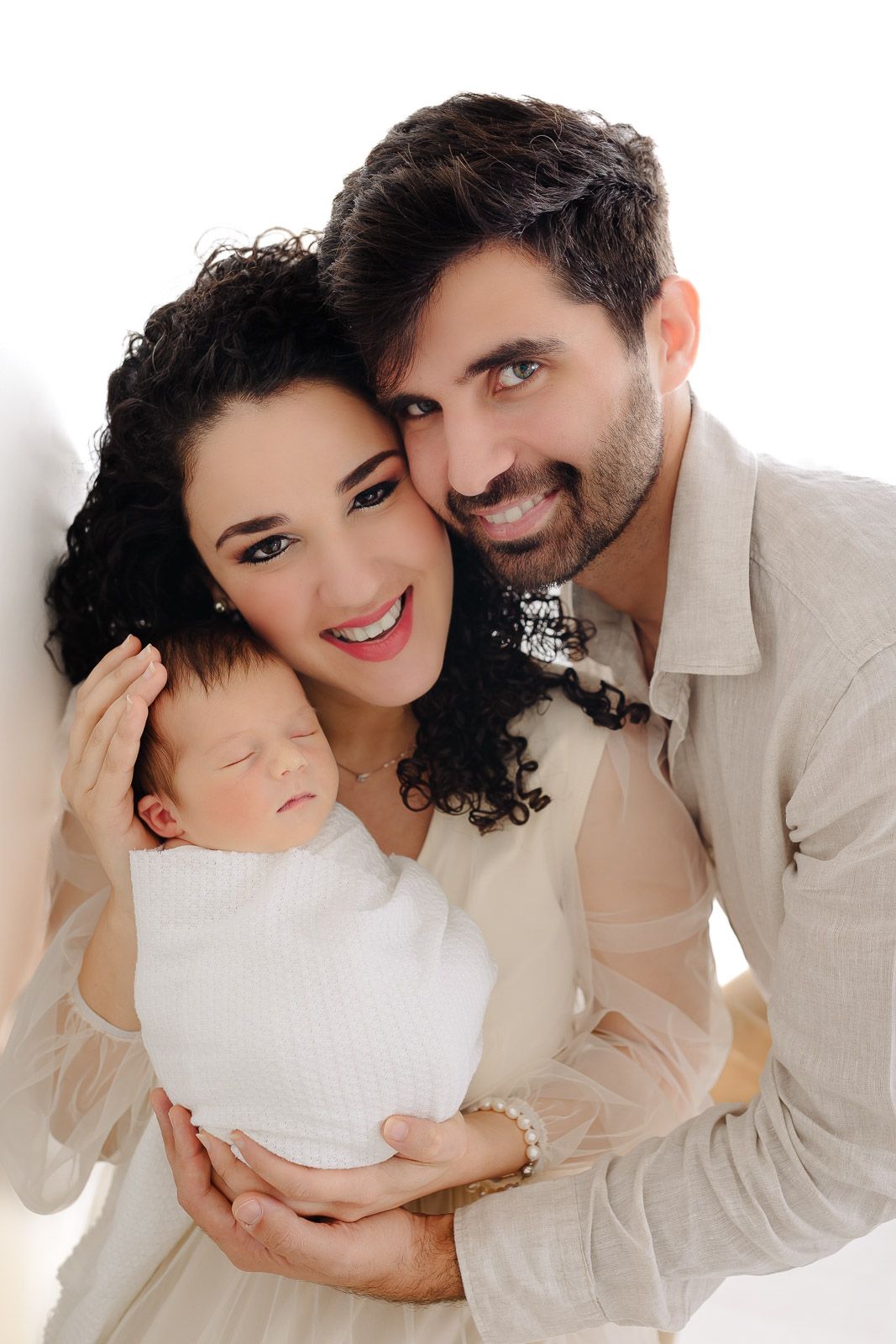 A romantic couple in white and beige outfits pose together in a series of intimate studio portraits.