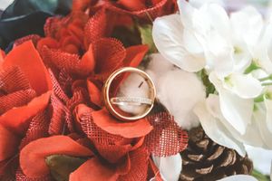 Red and white roses with wedding rings nestled among the petals in a romantic floral arrangement.