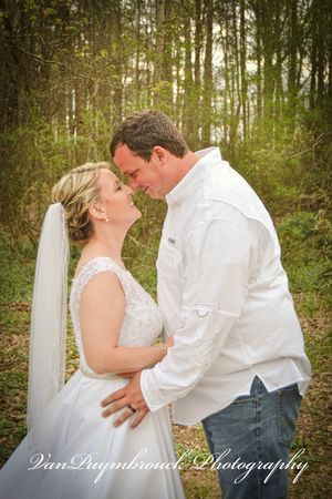 A romantic wedding couple shares intimate moments in a wooded setting with soft natural lighting.
