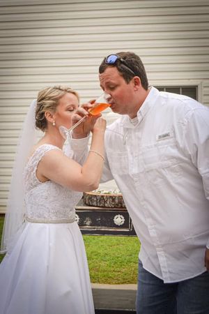 A couple in wedding attire shares a drink together during their celebration.