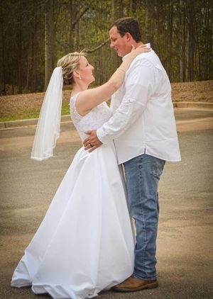 A couple shares an intimate moment during their outdoor wedding ceremony, with the bride in white and groom in casual attire.