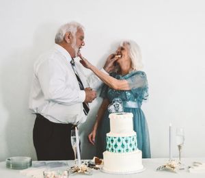 A couple cutting and feeding each other wedding cake at their reception with teal blue accents.