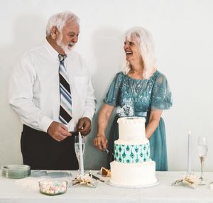 A sequence showing a couple cutting into a white and blue wedding cake at a celebration.