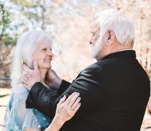 Elderly couple sharing tender moments in a romantic outdoor photo collage with soft pink cherry blossoms in background.