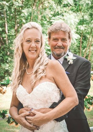 A happy couple shares joyful moments in an outdoor wedding photoshoot surrounded by lush green trees.