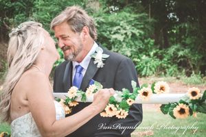 A tender moment shared between a bride and groom during an outdoor wedding ceremony with lush greenery in the background.