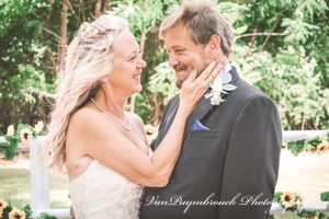 A couple shares a joyful moment during their outdoor wedding ceremony surrounded by lush greenery.