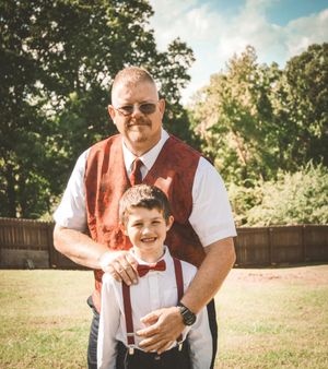 A heartwarming outdoor portrait of two people in matching bow ties and formal attire standing together in a backyard setting.