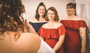 Group of women in red and white dresses smiling and posing together at a formal event.