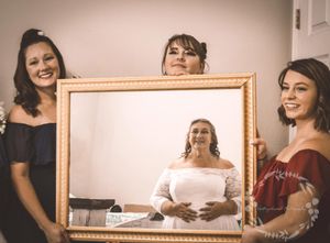 People gather around a table in a bright room with a mirror on the wall during a social gathering.