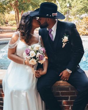 A couple shares a romantic moment in formal wedding attire by a poolside on a sunny day.